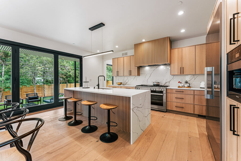 A finished Homestead kitchen, white oak, quartz island and sliding doors onto the deck